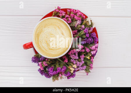 Cup of fresh hot coffee and statice flowers. Top view. White wood background. Stock Photo