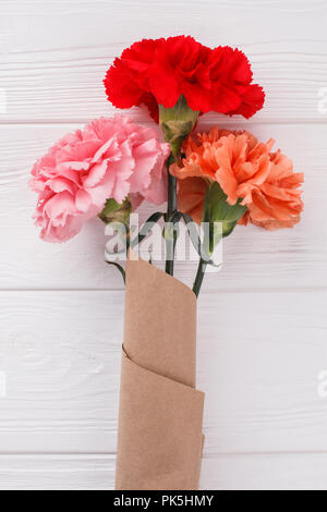 Paper bouquet of carnation flowers. White wood background. Close up. Stock Photo