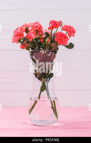 Rose bouquet in a vase. Pink wooden background. Stock Photo