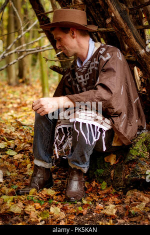 A middle aged man sits having a cigarette in a forest environment Stock Photo