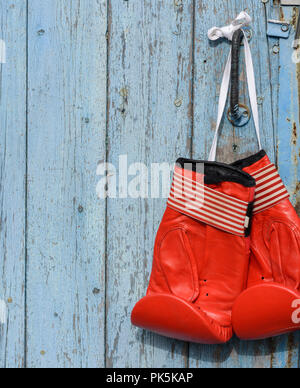 pair of red leather boxing gloves hanging on an old blue wooden wall, copy space Stock Photo