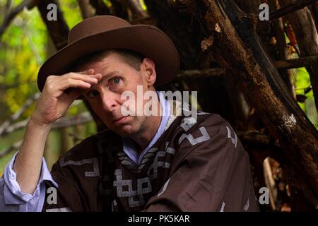 A middle aged man sits having a cigarette in a forest environment Stock Photo