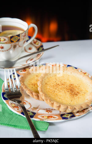 An English high tea of homemade Custard tart with lemon tea served on Roslyn bone China 8508 tea service Stock Photo