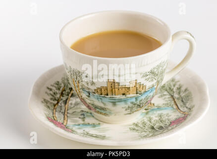 Beautiful vintage teacup with tea and saucer decorated with English castle scene Stock Photo