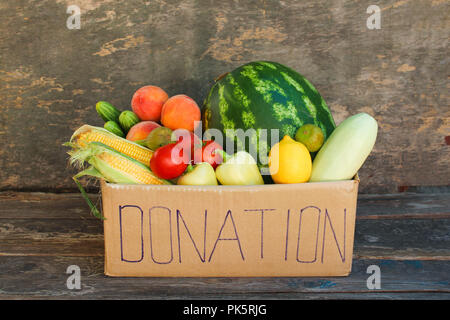Donation box with vegetables and fruits on the old wooden background. Stock Photo
