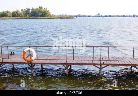 image life buoy hanging on the pier bridge near the water Stock Photo