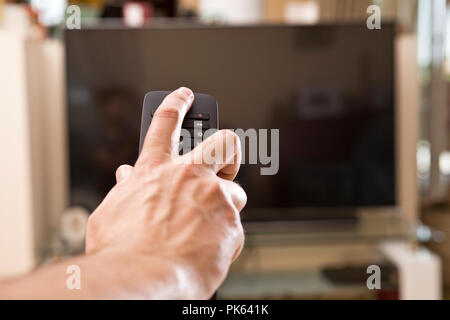 Yong man hand with remote changes channels Stock Photo
