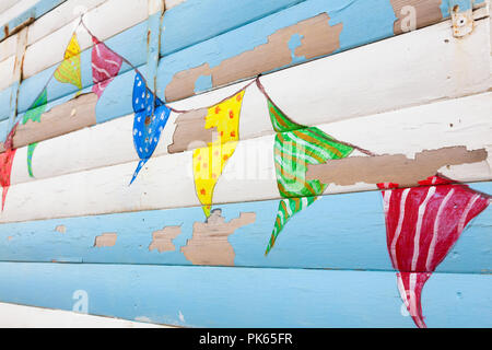 Peeling paint and bunting flags on a seaside beach hut, Kent, UK Stock Photo