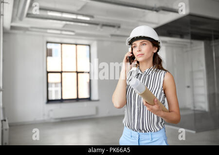 architect with blueprint calling on cell at office Stock Photo