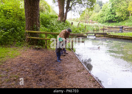 Four year old boy with his grandfather at Meon Springs Trout fishery, East Meon, Hampshire, England, United Kingdom. Stock Photo