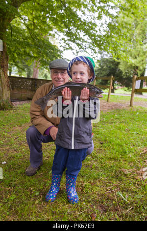 Four year old boy with his grandfather at Meon Springs Trout fishery, East Meon, Hampshire, England, United Kingdom. Stock Photo