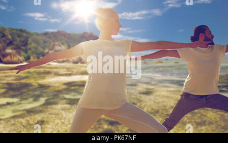 man and woman making yoga exercises on beach Stock Photo