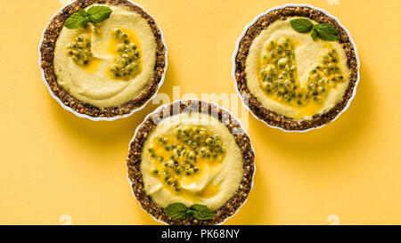 banner of vegan raw mini tarts from nuts and dates with cashew cream from mango purée with lime juice and seeds of passion fruit. healthy alternative 