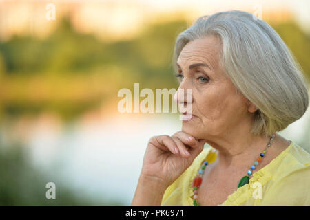 Portrait of beautiful sad senior woman in park Stock Photo