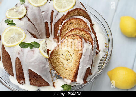 Above shot of lemon cream cheese bundt cake with cream cheese filling in the center cut into slices. Fresh lemons in background. Extreme shallow depth Stock Photo