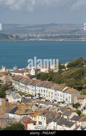 Houses that form part of the village of Fortuneswell on the Isle of Portland with Portland Harbour behind them. Dorset England UK GB Stock Photo