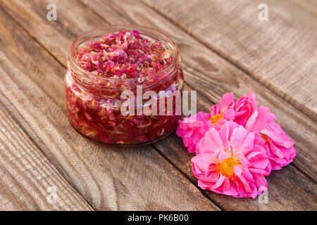 Jam jar of rose petals on wooden background. Stock Photo