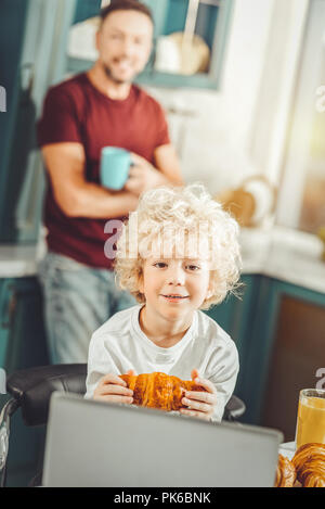 Curly blonde-haired boy watching cartoon on laptop Stock Photo