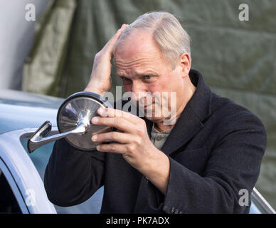Friedberg, Hessen. 11th Sep, 2018. Actor Ulrich Tukur looks into a broken off car mirror on the set at the edge of the shooting for a new crime scene of the Hessischer Rundfunk (HR). The eighth HR crime scene with Ulrich Tukur is created under the working title 'The Attack'. Credit: Frank Rumpenhorst/dpa/Alamy Live News Stock Photo