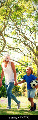 Mother and son walking in the park with football Stock Photo