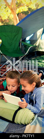 Siblings using laptop outside the tent Stock Photo