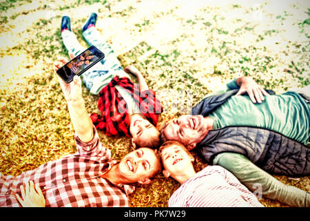 Happy family lying on the grass and taking selfie Stock Photo