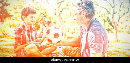 Father and son playing with football in park Stock Photo