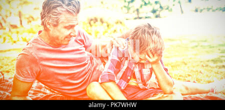 Father consoling his son at picnic in park Stock Photo