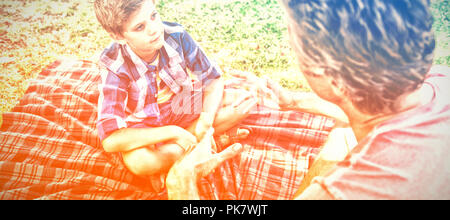 Father talking to son at picnic in park Stock Photo
