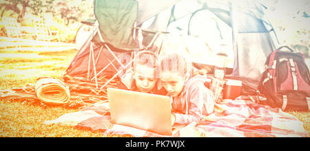 Siblings using laptop outside the tent Stock Photo