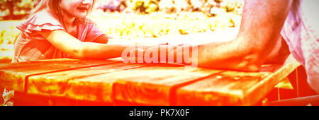 Mother and daughter holding hands on picnic table Stock Photo
