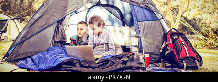 Kids using laptop in the tent Stock Photo