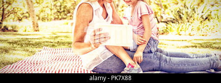 Happy mother and daughter using digital tablet in park Stock Photo
