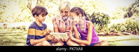 Grandmother and grand kids using digital tablet in the park Stock Photo