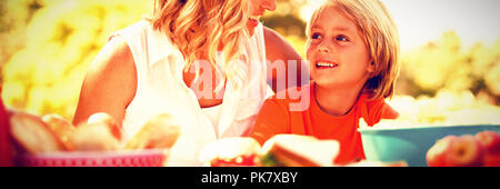 Mother and son interacting with each other while having meal in park Stock Photo