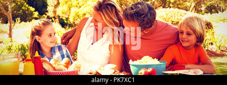 Happy family interacting with each other while having meal in park Stock Photo