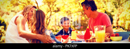 Happy family interacting with each other while having meal in park Stock Photo