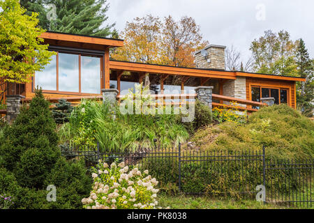 Rear view of luxurious stained cedar and timber wood home with panoramic windows and landscaping in autumn, Quebec, Canada Stock Photo