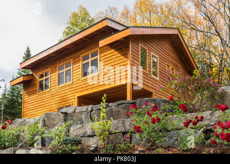 Luxurious stained cedar and timber wood 2-car garage with upstairs floor and landscaping in autumn, Quebec, Canada Stock Photo