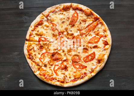 top view of italian pizza with mozzarella cheese and tomatoes on dark brown wooden board Stock Photo