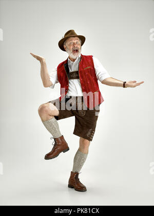 Portrait of Oktoberfest senior man in hat, wearing a traditional Bavarian clothes standing at full-length at studio. The celebration, oktoberfest, festival concept Stock Photo