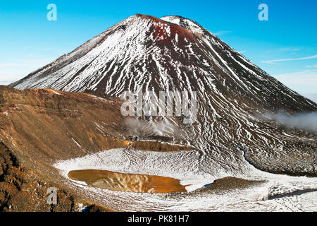 Amazing nature wonder, huge active volcano with red peak above sulphide water lake with mirror reflection of the snow covered mountain, New Zealand Stock Photo