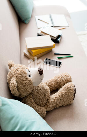 high angle view of teddy bear on couch with school supplies at home Stock Photo