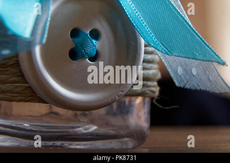 Closeup Decorative jar with bow and blue stones inside on wooden table, mock-up for postcard or greeting card. Stock Photo