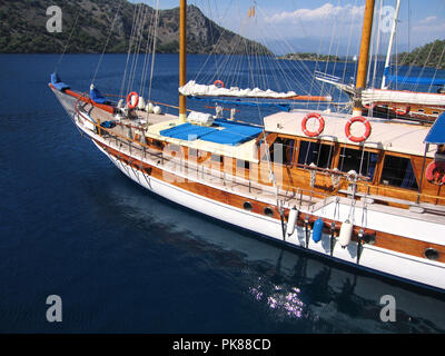 Traditional pretty tourist gulet boat anchored in calm water in Fethiye Turkey on a sunny day Stock Photo