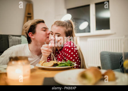 Happy young couple are being romantic while enjoying dinner together at home. Stock Photo