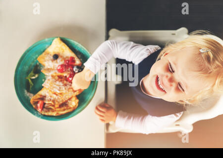 cute funny little girl eating pancakes with berries