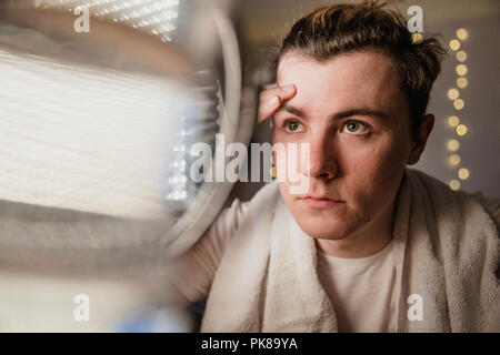Young man is applying face cream in a mirror at home. Stock Photo
