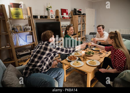 Two couples are having a dinner party at home and are toasting their drinks before they eat. Stock Photo