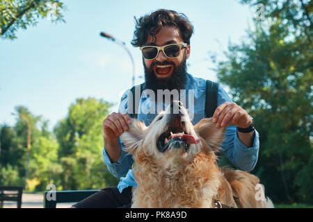 Man and dog having fun, playing, making funny faces while resting in the park. Life is beautiful, best friends concept. Stock Photo